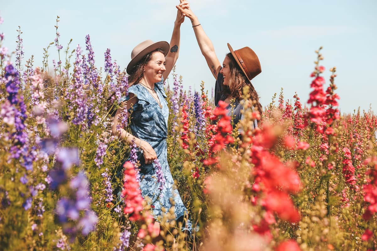 two women in a field of flowers holding hands